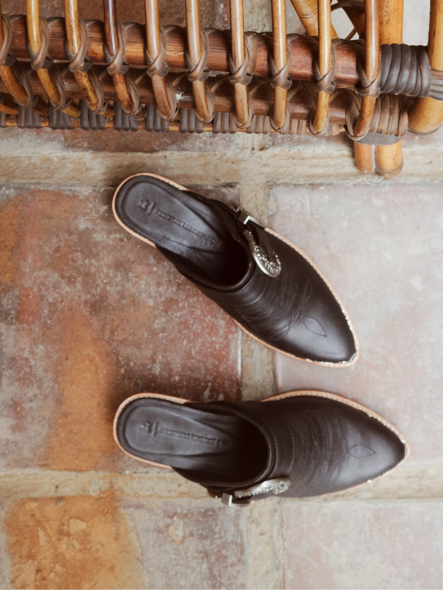 Black pointy toe mules by Seminyak Leather Bali with western-style stitching on vamp and carved metal toe cap. 5 cm wooden Cuban heel in a natural finish. A blend of Western charm and contemporary elegance, all made of leather.