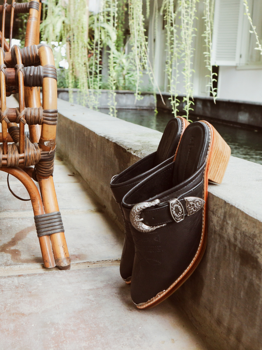 Black pointy toe mules by Seminyak Leather Bali with western-style stitching on vamp and carved metal toe cap. 5 cm wooden Cuban heel in a natural finish. A blend of Western charm and contemporary elegance, all made of leather.