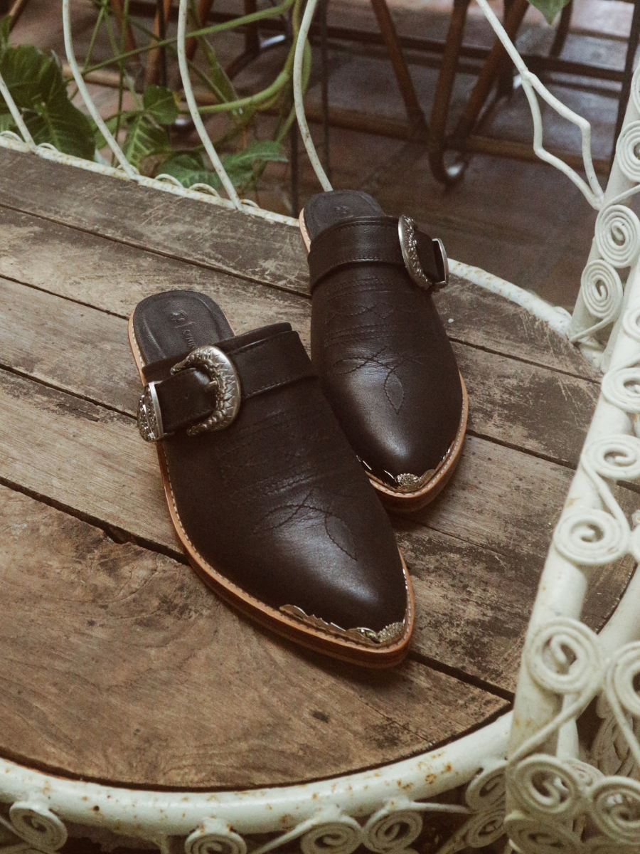 Black pointy toe mules by Seminyak Leather Bali with western-style stitching on vamp and carved metal toe cap. 5 cm wooden Cuban heel in a natural finish. A blend of Western charm and contemporary elegance, all made of leather.