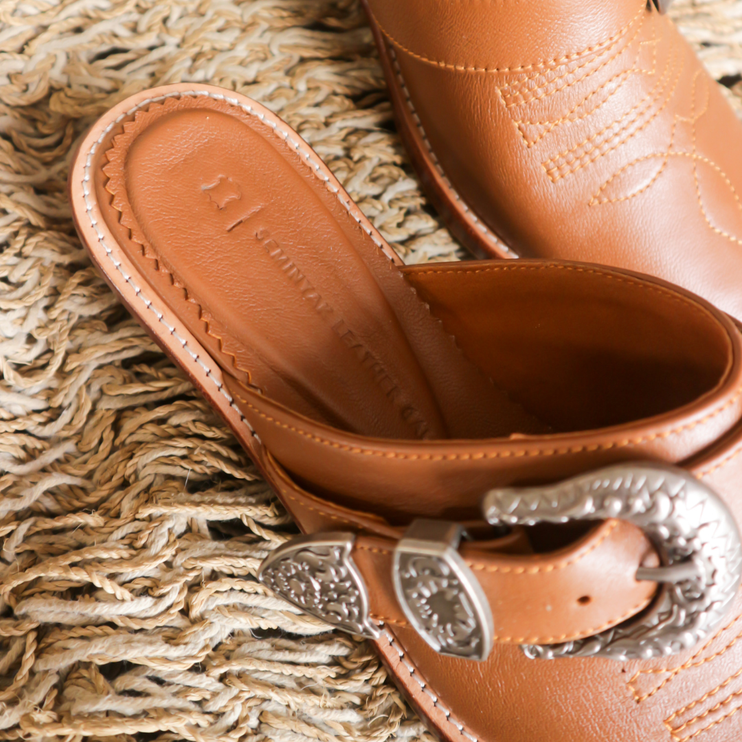 Brown pointy toe mules by Seminyak Leather Bali with western-style stitching on vamp and carved metal toe cap and carved buckle. 5 cm wooden Cuban heel in a natural finish. A blend of Western charm and contemporary elegance, all made of leather.