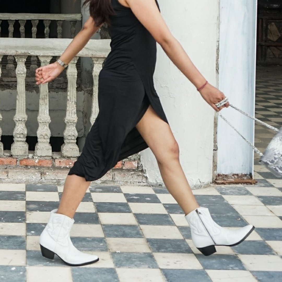 Ankle boots with handstitched detailing, featuring zipper closure and carved metal accents on the toe cap and heel. 5 cm wooden heel in a classic black finish. Stylish footwear inspired by cowboy/ western ankle boots for a touch of rustic charm and modern allure.