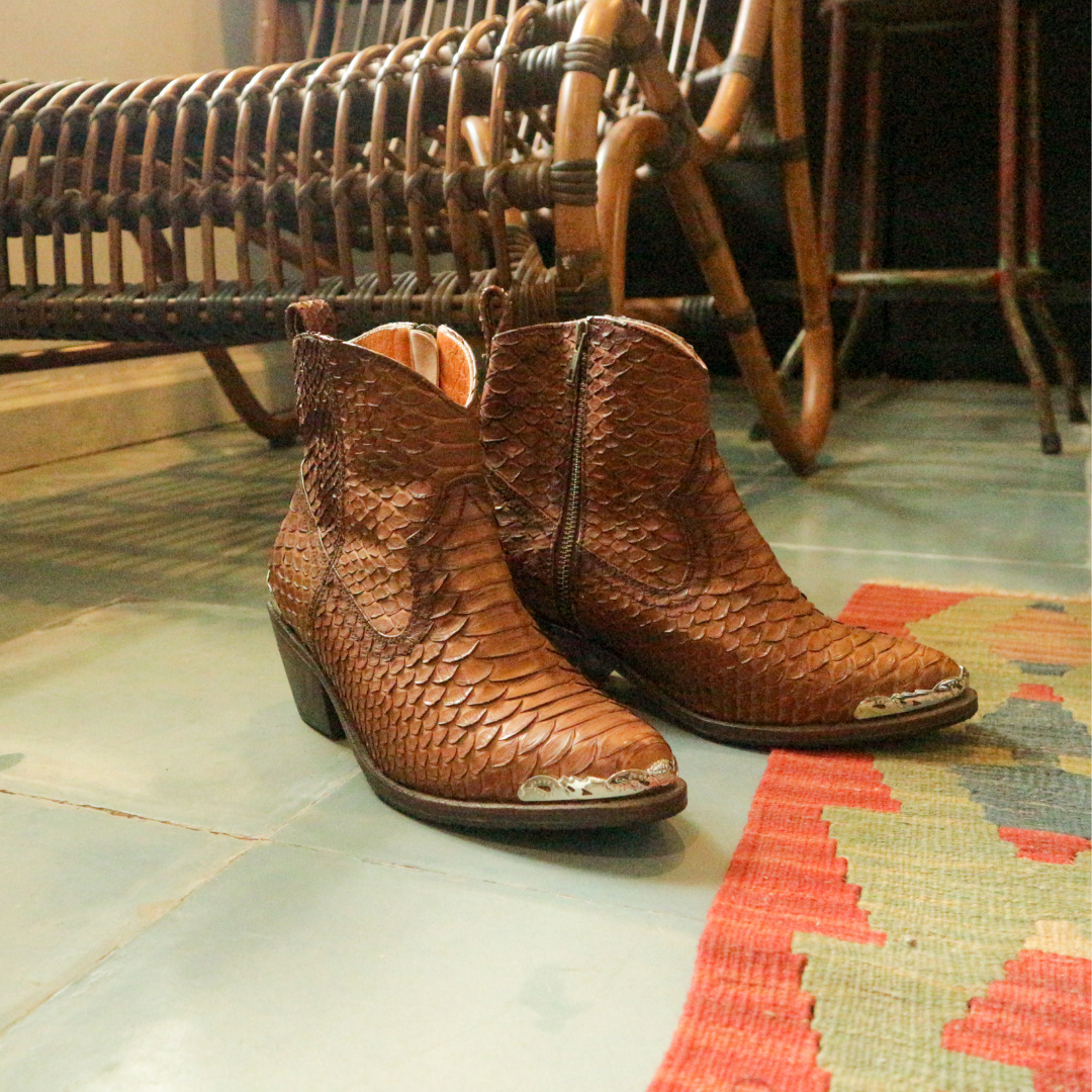 Ankle boots by Seminyak Leather Bali made of snakeskin leather in antique brown color. Loose fit cut with carved metal detailing on the toe cap and heel. 5 cm wooden Cuban-style heel. Zipper closure. Edgy and chic footwear for bold fashion statements.