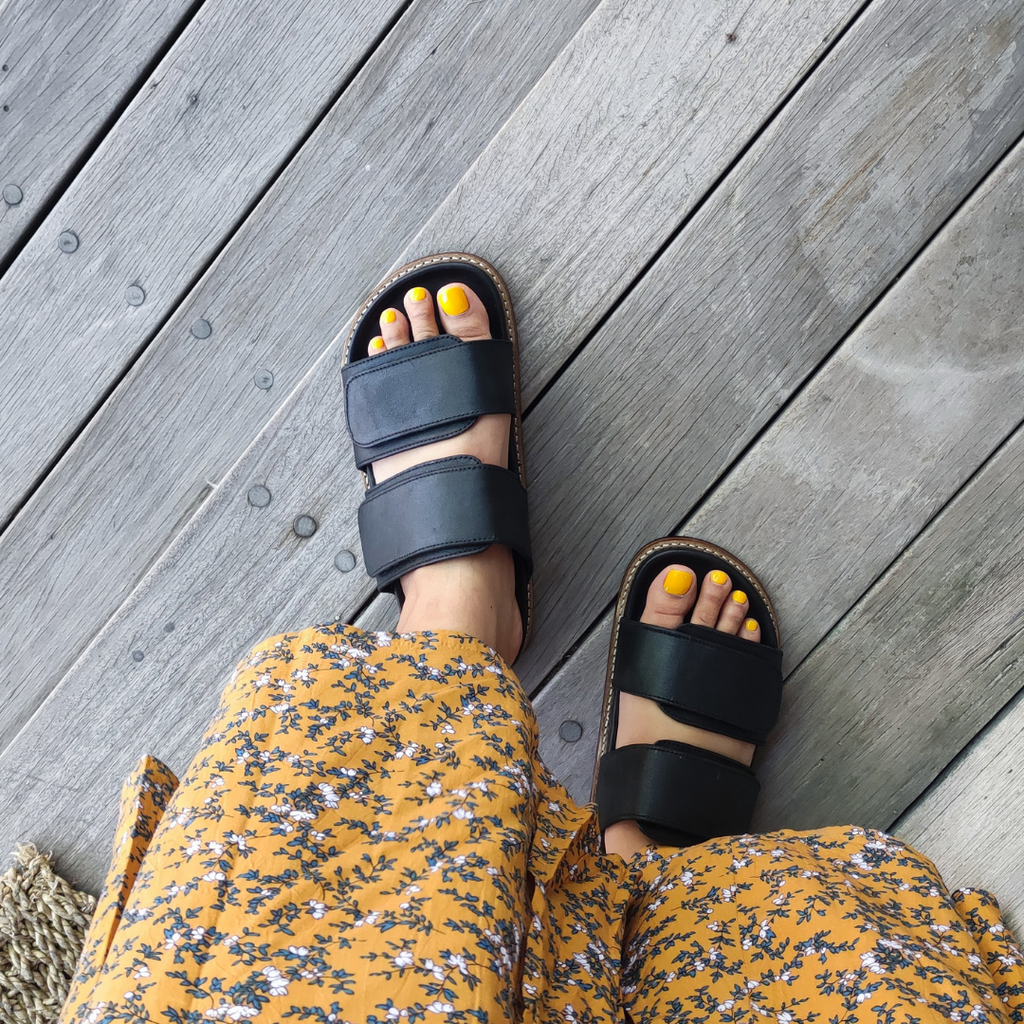 wearing a pair of black MURI slides leather shoes